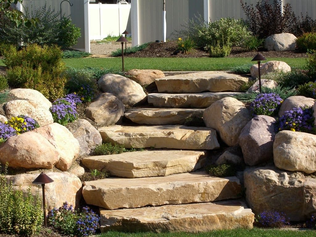 Natural stone garden steps surrounded by colorful flowers and landscaping features.