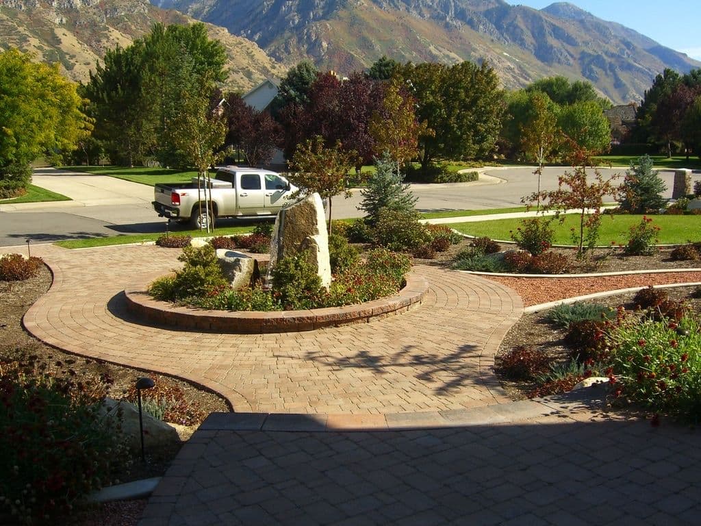 Scenic driveway with paver path, landscaped gardens, and mountains in the background.