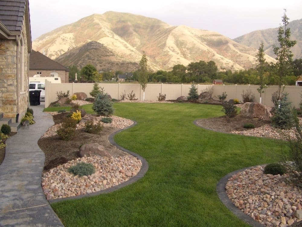 Lush landscaped yard with stone pathways and mountains in the background.