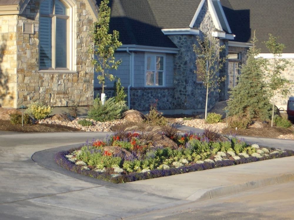 Colorful flowerbed with rock features in a landscaped front yard of a residential home.
