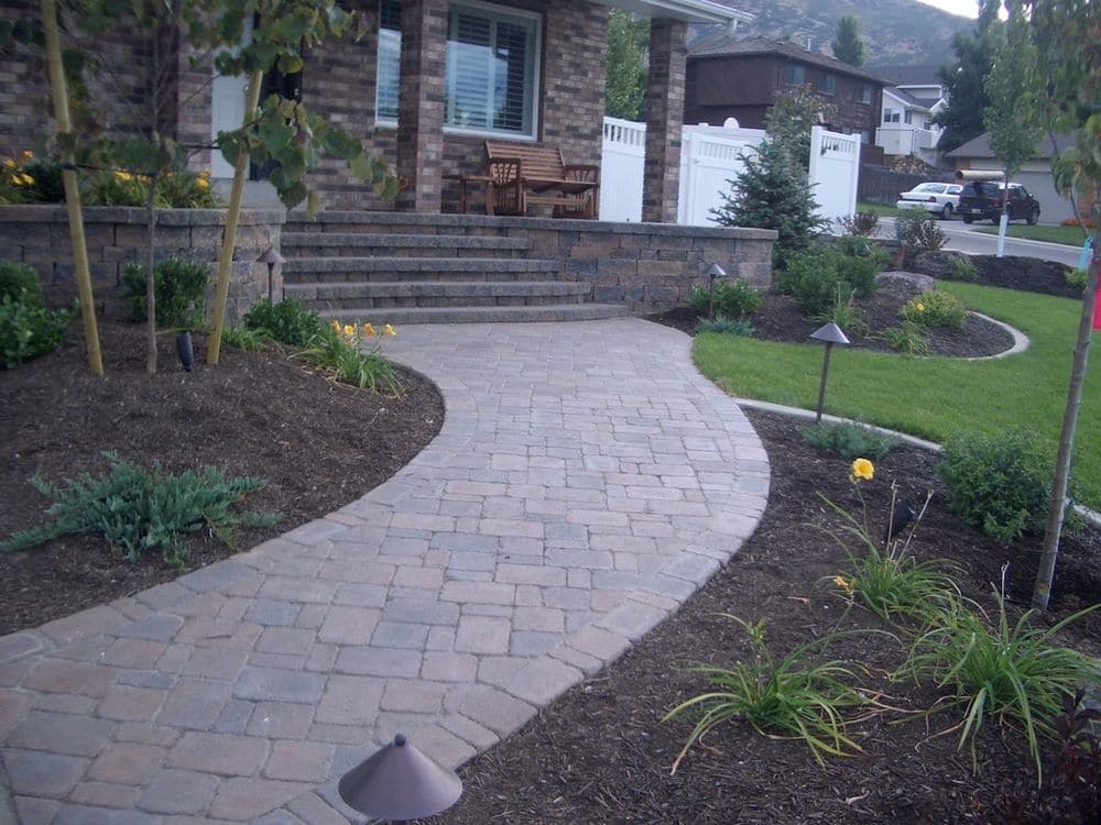 Curved stone pathway leading to a modern brick home with landscaped garden.